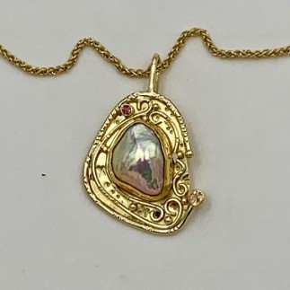 18k yellow gold pendant with a metallic, fresh water keshi pearl set in 22k yellow gold with two natural color orange sapphires