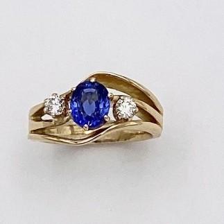 Three wave ring in 18k yellow gold with a 1.27 ct. blue sapphire (h) and a .10 ct. ideal cut, "E: color, VS clarity diamond on each side. Prong settings are 14k yellow gold.