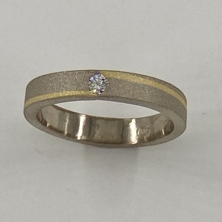 18k palladium white gold with 18k yellow gold inlay with .10ct. E color, VS clarity diamond in the center.
