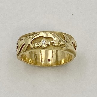 6.5 mm wide, 18k yellow gold band with a vine and flower motif with a .01ct. diamond in each of the four flowers around the band