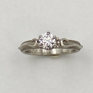 Simple engagement ring in 950 platinum with a frosted background and a .46 ct. ideal cut Lazare Diamond, “D” color, VS1 clarity.