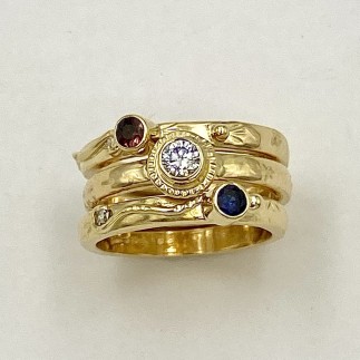 18k yellow gold, three ring stacking set with a .15 ct., E color, VS clarity diamond, a .13 ct., natural color orange sapphire and a .11 ct. blue sapphire (H) with  two .o15 ct., diamonds in the loops.