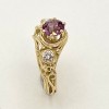 18k yellow gold looping wire and bead ring with a 1.39 ct., pinkish purple sapphire (H) with .15 ct. E color, VS clarity diamond on either side.