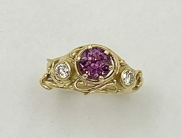 18k yellow gold looping wire and bead ring with a 1.39 ct., pinkish purple sapphire (H) with .15 ct. E color, VS clarity diamond on either side.