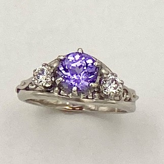 950 platinum ring with a 1.31 ct. natural color, Sri Lankan purple sapphire flanked by .15 ct. E color, VS clarity ideal cut diamonds.