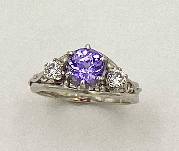 950 platinum ring with a 1.31 ct. natural color, Sri Lankan purple sapphire flanked by .15 ct. E color, VS clarity ideal cut diamonds.