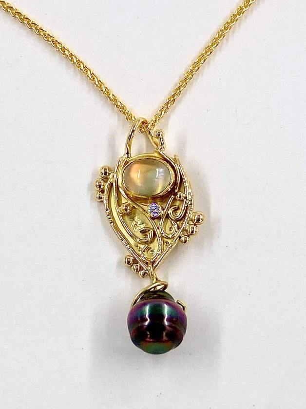 18k yellow gold pendant with a 3.35 ct. original source rainbow moonstone with a 22k bezel setting, a .05 ct. diamond E color, VS clarity and a black South Sea pearl. Chain is priced separately.