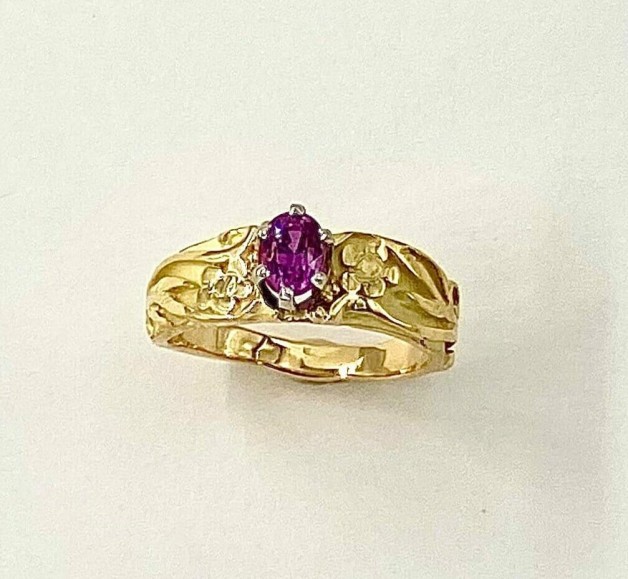 18k yellow gold ring with a .88 ct. (H) hot pink sapphire in a 6 prong platinum setting with floral designs on the sides.
