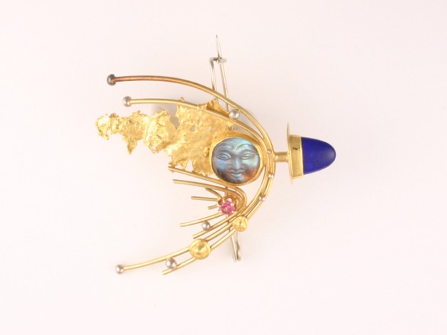 Boston jeweler Daniel Spirer handcrafted this 18k and 22k gold comet pin with lapis lazuli, pink sapphire and carved labradorite face